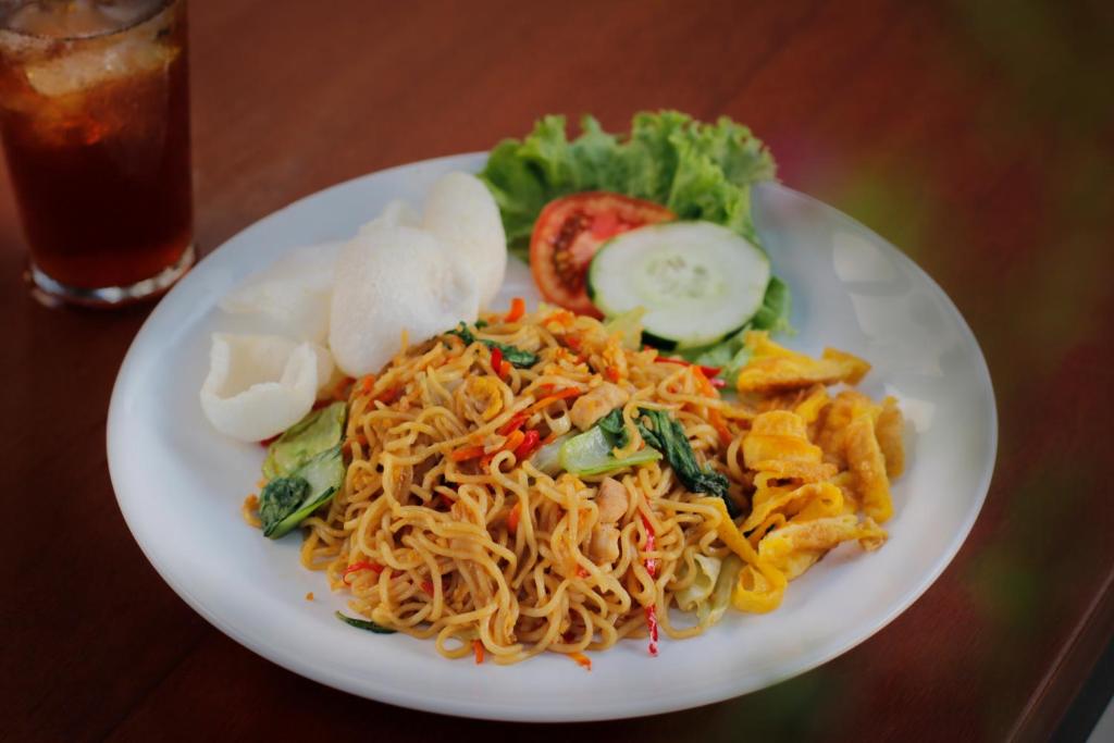 a plate of food with noodles and vegetables on a table at Bingin Lodge Uluwatu in Uluwatu