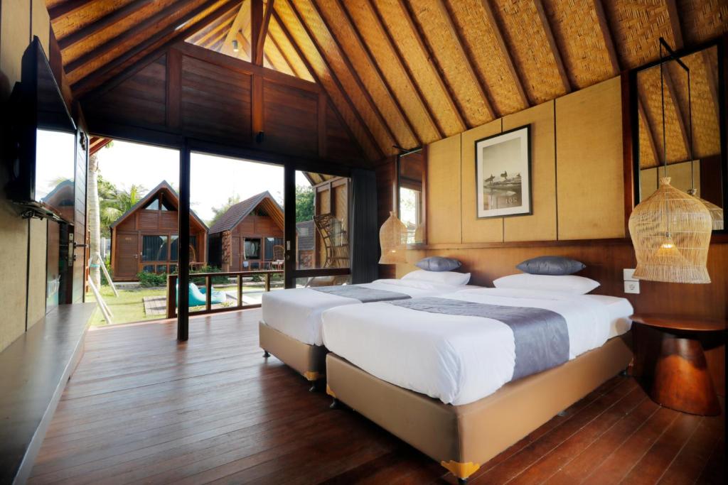 a bedroom with two beds and a large window at Bingin Lodge Uluwatu in Uluwatu