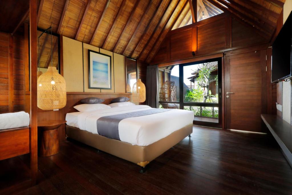 a bedroom with a large bed and a large window at Bingin Lodge Uluwatu in Uluwatu