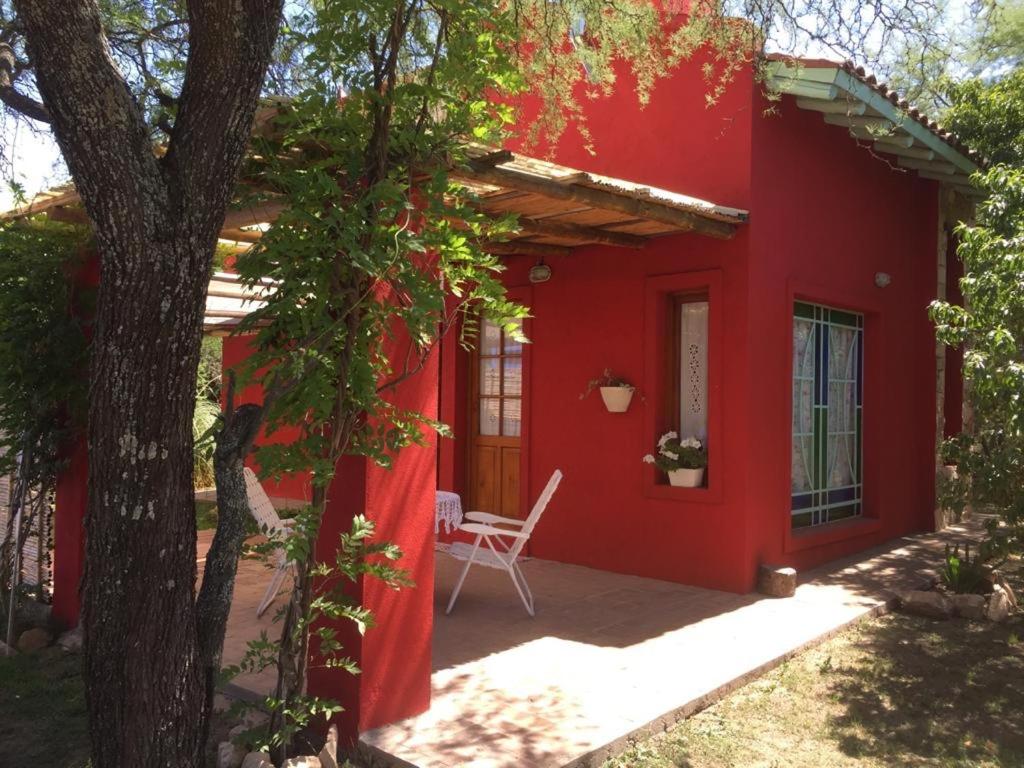 una casa roja con una silla blanca delante en Raco De La Calma en Nono