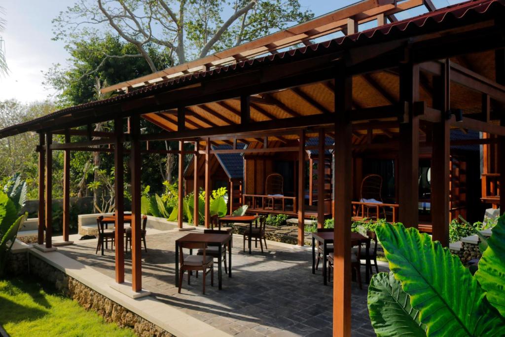 a wooden pavilion with tables and chairs in a garden at Bingin Lodge Uluwatu in Uluwatu