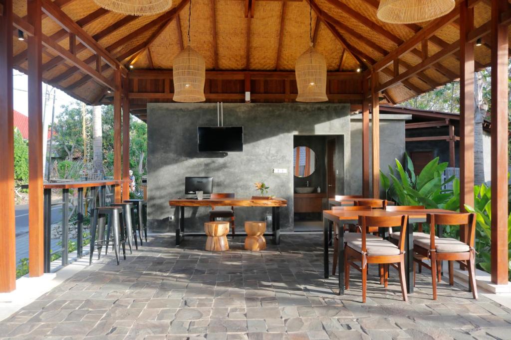 a patio with wooden tables and chairs and a tv at Bingin Lodge Uluwatu in Uluwatu