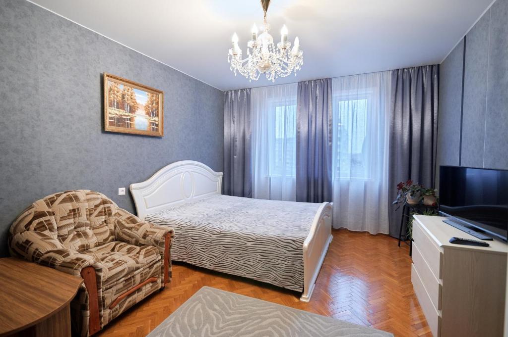 a bedroom with a bed and a chair and a television at Holiday and Travel Apartment in Brest