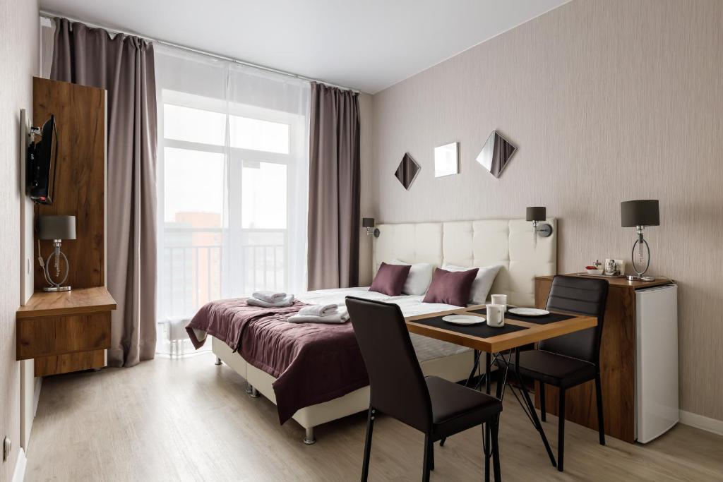 a bedroom with a bed and a table and chairs at Salut Plus Apartments in Saint Petersburg