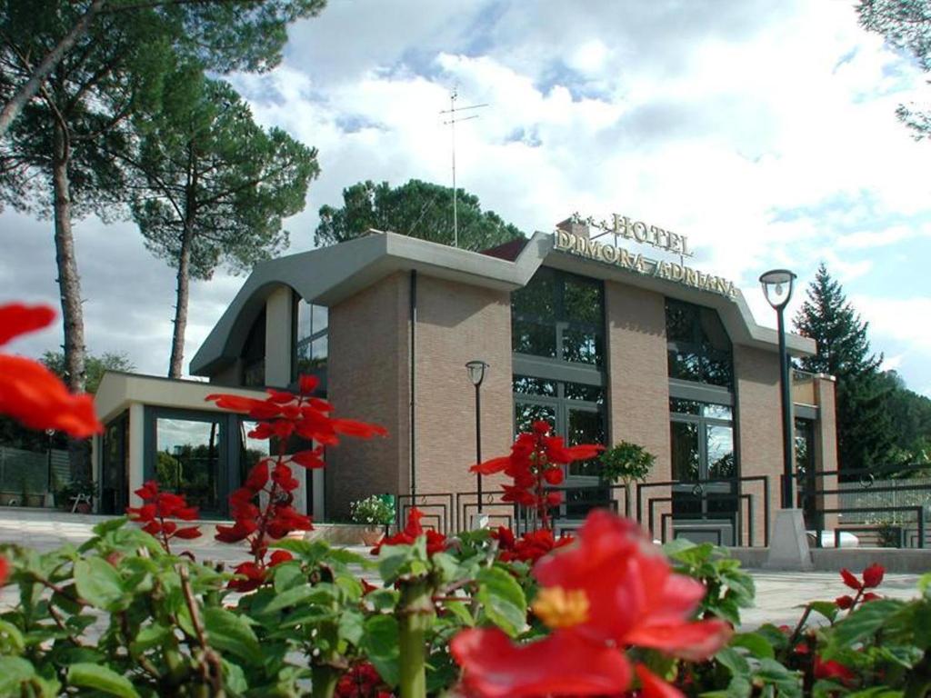 un edificio con flores rojas delante de él en Hotel Dimora Adriana, en Tívoli