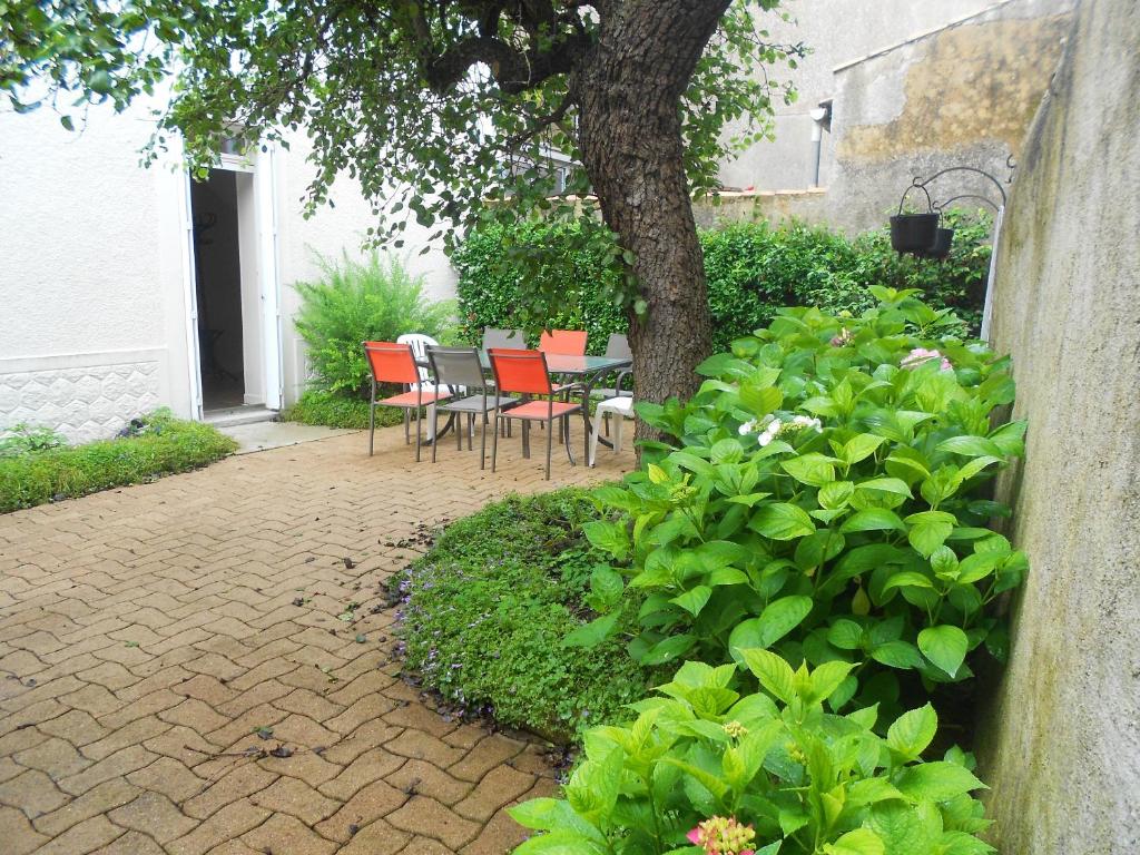 eine Terrasse mit einem Tisch, Stühlen und einem Baum in der Unterkunft Maison de 3 chambres avec jardin clos et wifi a Airvault in Airvault