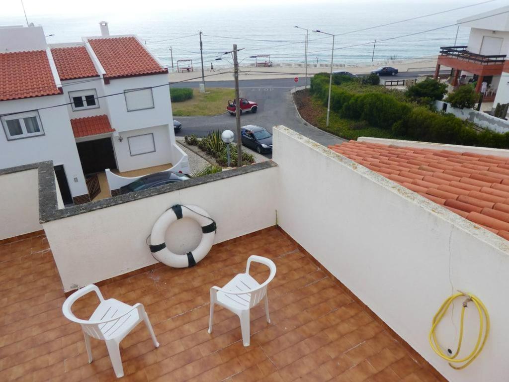 einen Balkon mit zwei Stühlen und einem Strandball auf dem Dach in der Unterkunft 5 bedrooms house at A dos Cunhados 50 m away from the beach with sea view enclosed garden and wifi in A dos Cunhados