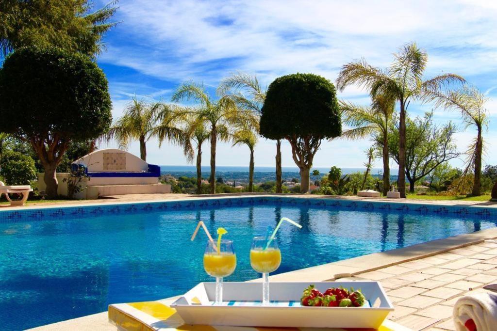 uma piscina com uma mesa com bebidas e frutas em 6 bedrooms villa with sea view private pool and wifi at Loule em Loulé