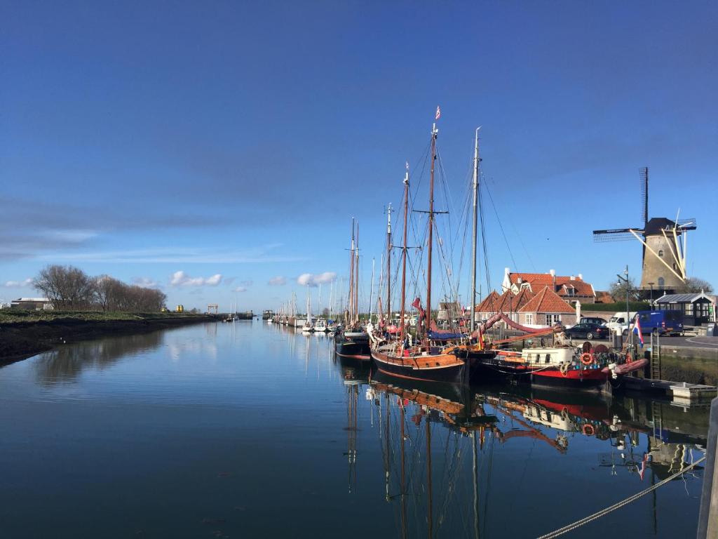 un grupo de barcos atracados en un canal con un molino de viento en Zierikzee Appartement ZZ 41 B&B, en Zierikzee