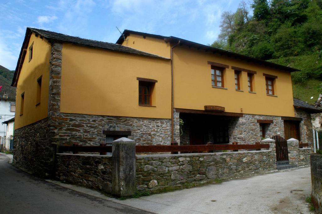 un bâtiment jaune avec un mur en pierre à côté d'une rue dans l'établissement Casa Xuaquin, à Moal