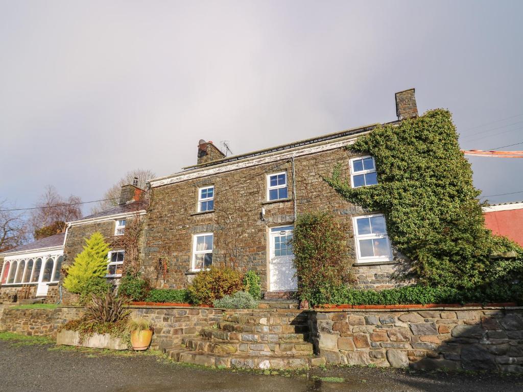 an old brick house with ivy growing on it at The Farmhouse in Ciliau-Aeron