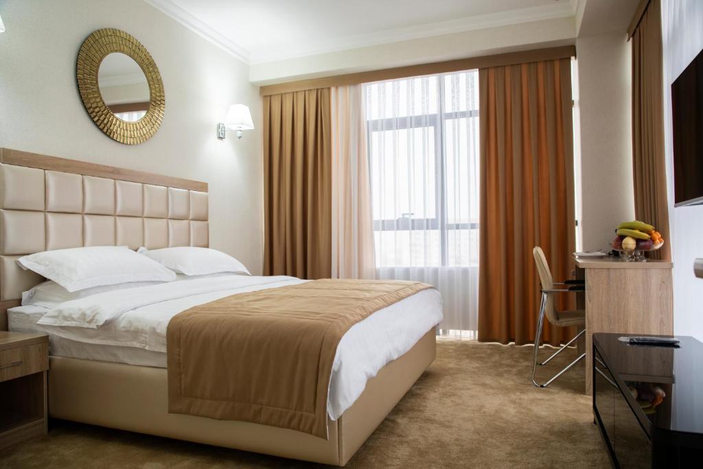 Pokój hotelowy z dużym łóżkiem i lustrem w obiekcie VELARA HOTEL w Taszkiencie