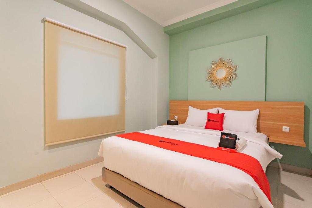 a bedroom with a large bed with a red blanket at RedDoorz Plus @ Bagusrangin Street in Bandung
