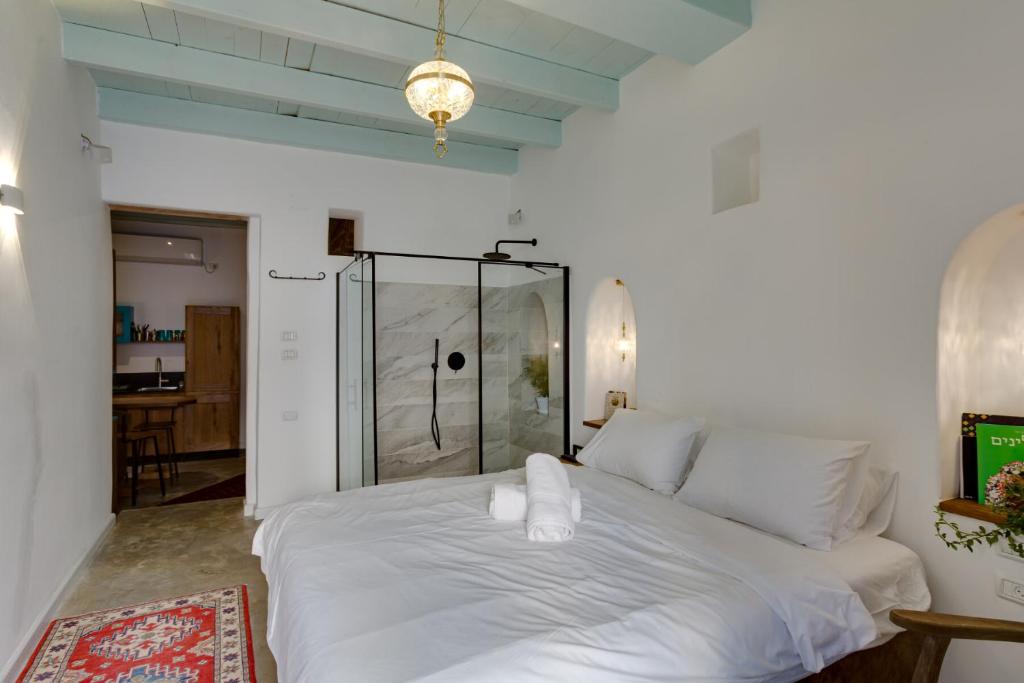 a bedroom with a white bed with a glass door at Daya - Old City Acre in Acre