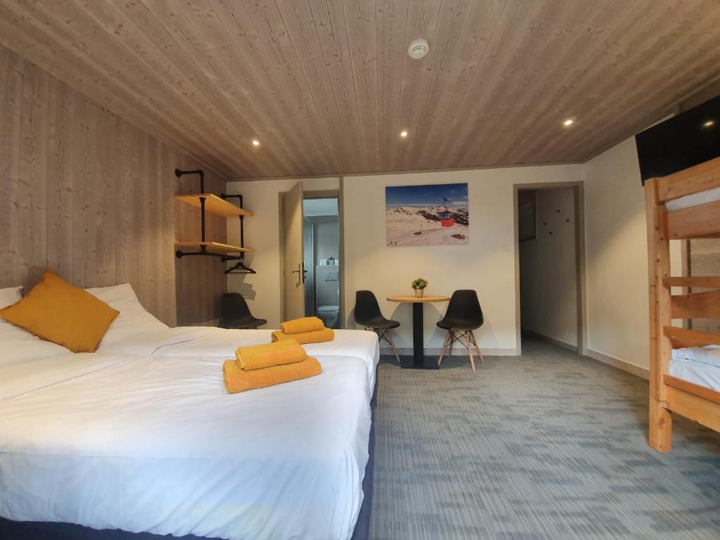 ein Hotelzimmer mit 2 Betten und einem Schreibtisch in der Unterkunft Lodge Les Merisiers in Courchevel