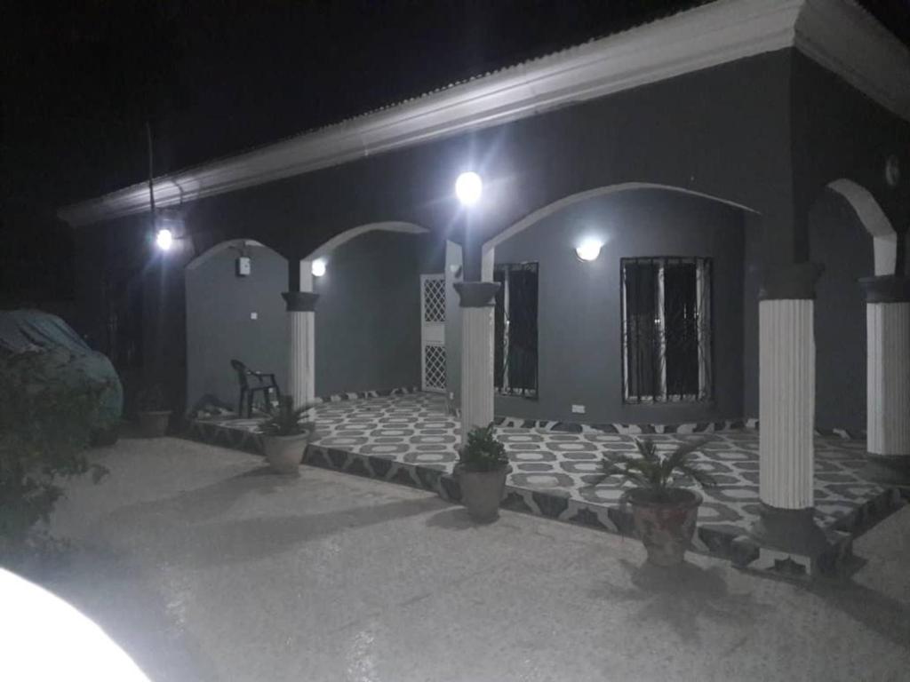 un bâtiment avec des plantes en pot devant lui la nuit dans l'établissement Remarkable 4-Bed with air conditioning in Brikama, à Brikama