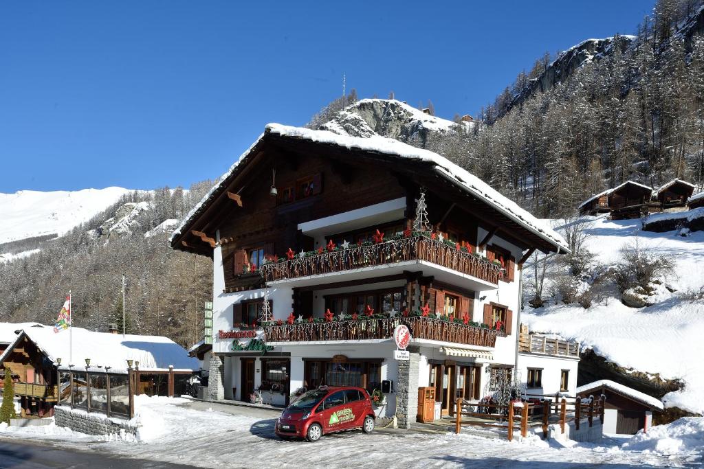 a building with a red car parked in front of it at Hotel Les Mélèzes in Haudères