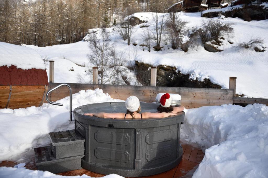 two people in a hot tub in the snow at Hotel Les Mélèzes in Haudères