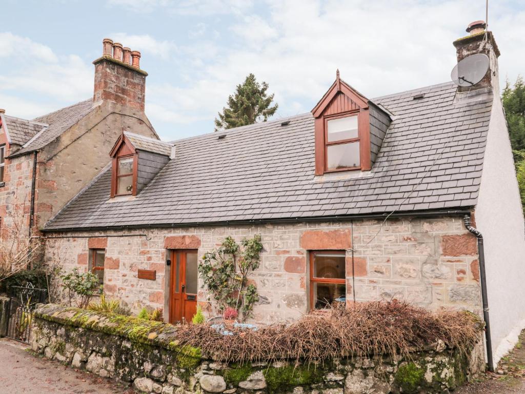 an old stone house with a gray roof at Stonywood Cottage in Drumnadrochit