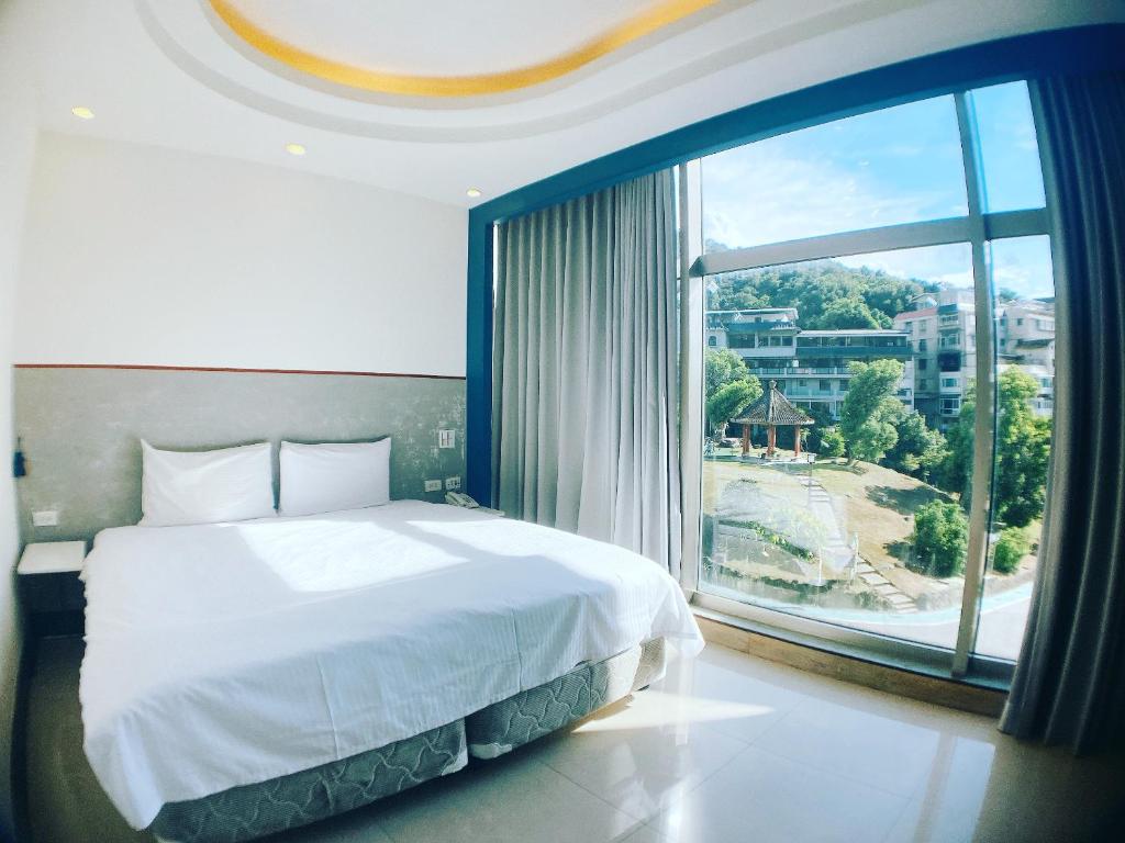 sypialnia z dużym łóżkiem i dużym oknem w obiekcie Spa Spring Resort w Tajpej