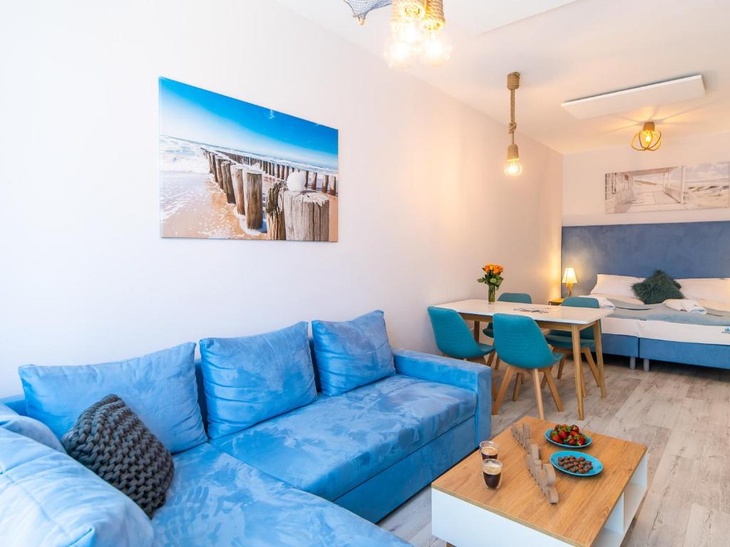 een woonkamer met een blauwe bank en een tafel bij ApartmentyPrzyMorzu Ogrody in Kołobrzeg