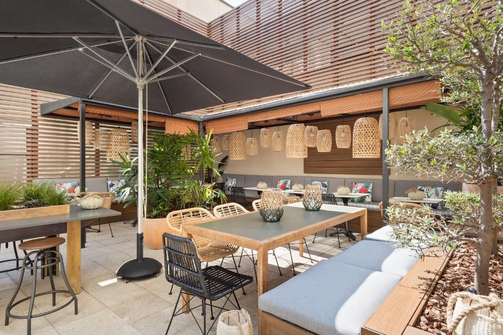 
a patio area with tables, chairs, and umbrellas at Hotel Barcelona Apolo, Affiliated by Meliá in Barcelona
