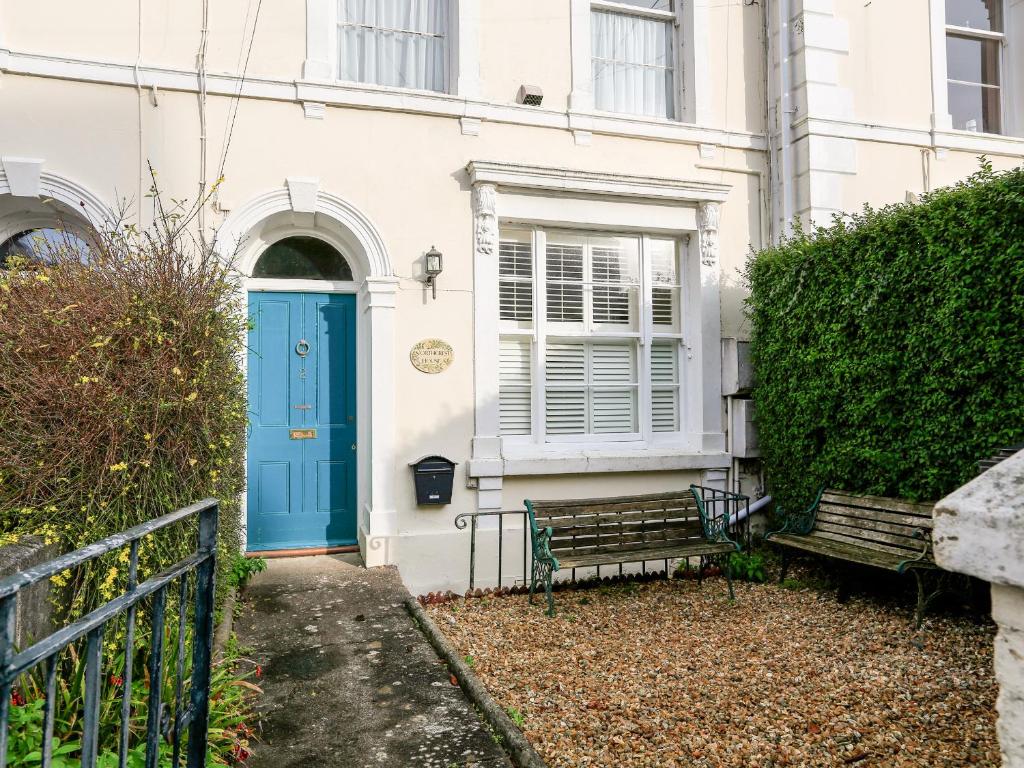 a blue door on a white house with a bench at 2 North Crest House in Salcombe