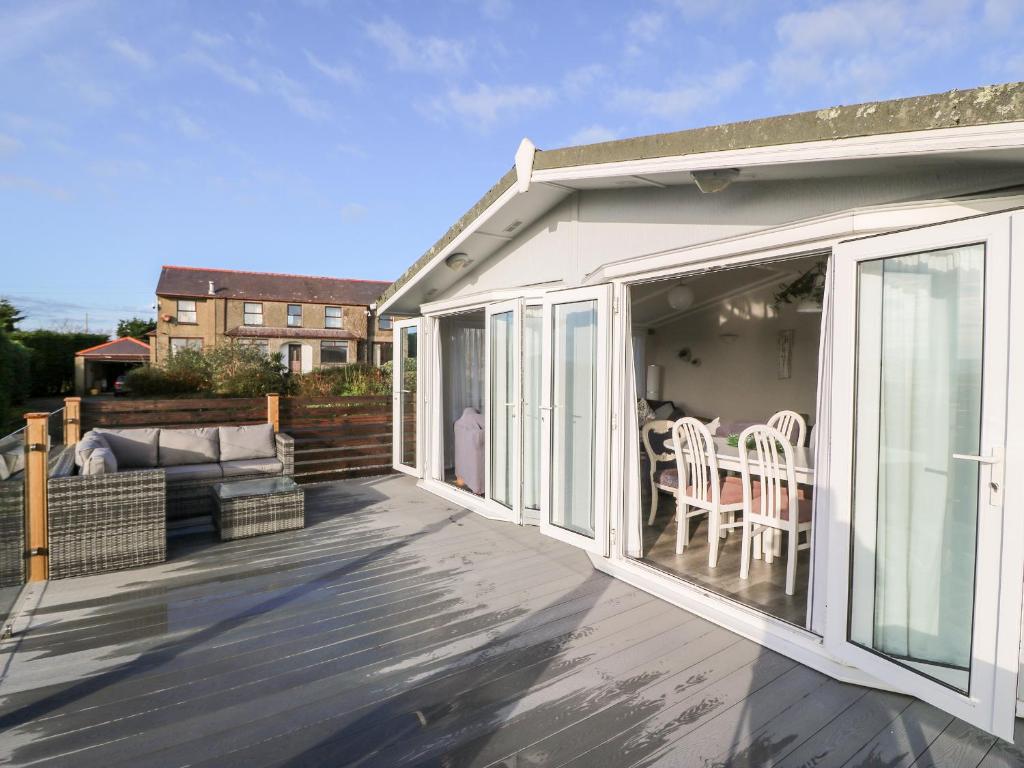 a patio with sliding glass doors and a table and chairs at Caban Tywod in Pwllheli