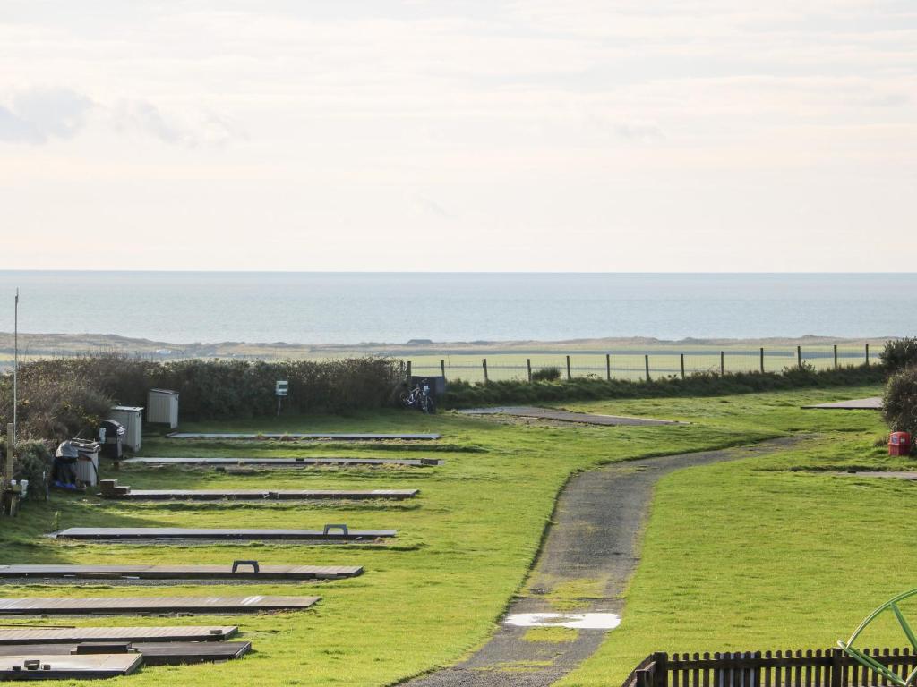 a row of bleachers on a field with the ocean in the background at Caban Tywod in Pwllheli
