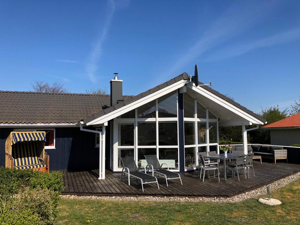 a house with a deck with a table and chairs at Strandhus - Haus 37 in Grömitz