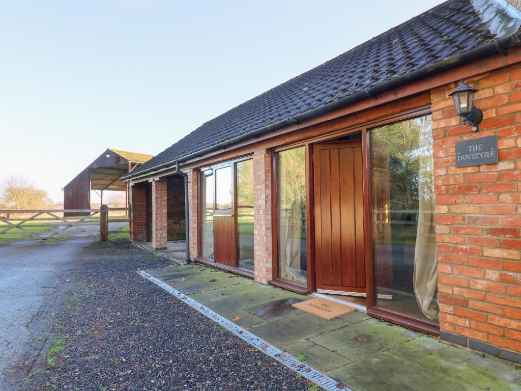 un edificio de ladrillo con puertas correderas de cristal. en Dovecote Field House Farm, en Newark-on-Trent