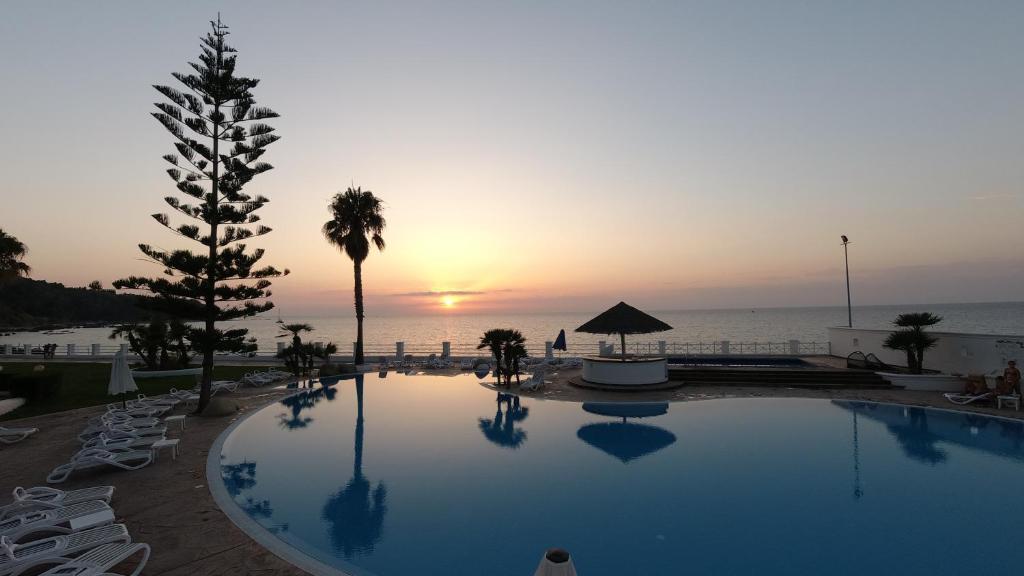 a large swimming pool with a sunset in the background at Cala Petrosa Resort in Parghelia