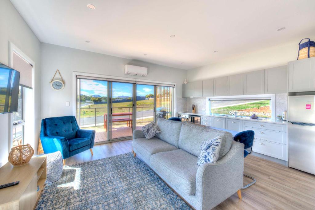 a living room with a couch and chairs and a kitchen at Archella 1 in Coles Bay
