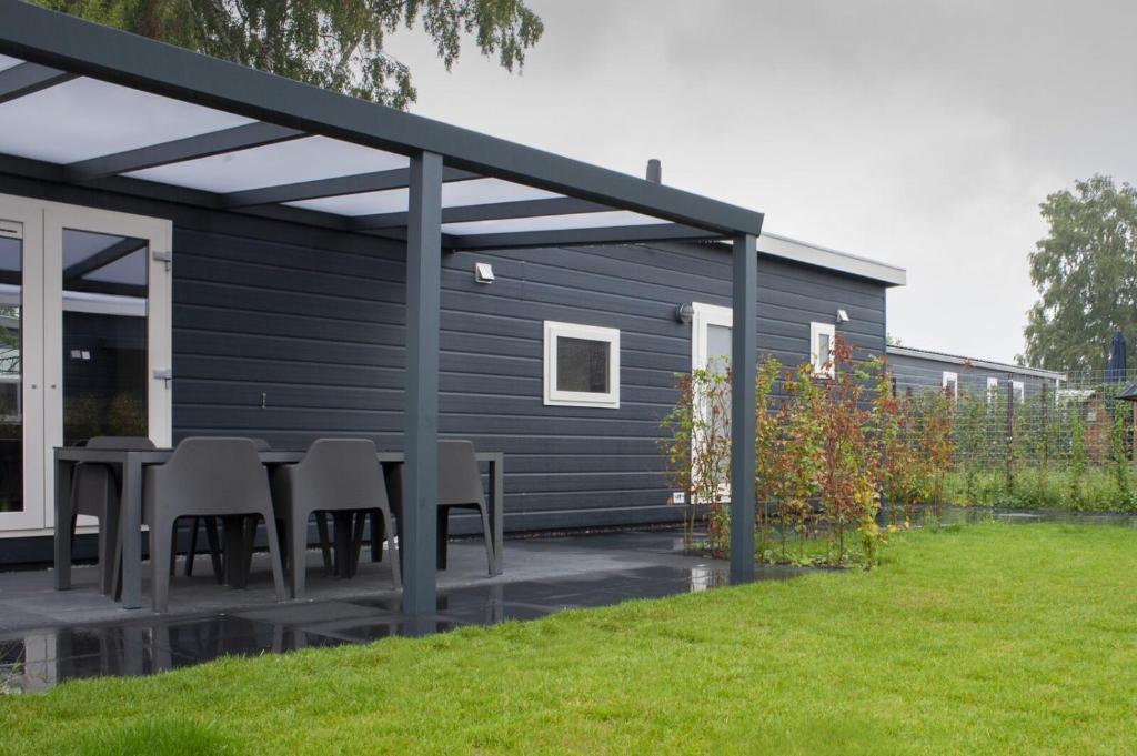 a black house with a table and chairs on a patio at 6-persoons Veluwelodge XL in Voorthuizen