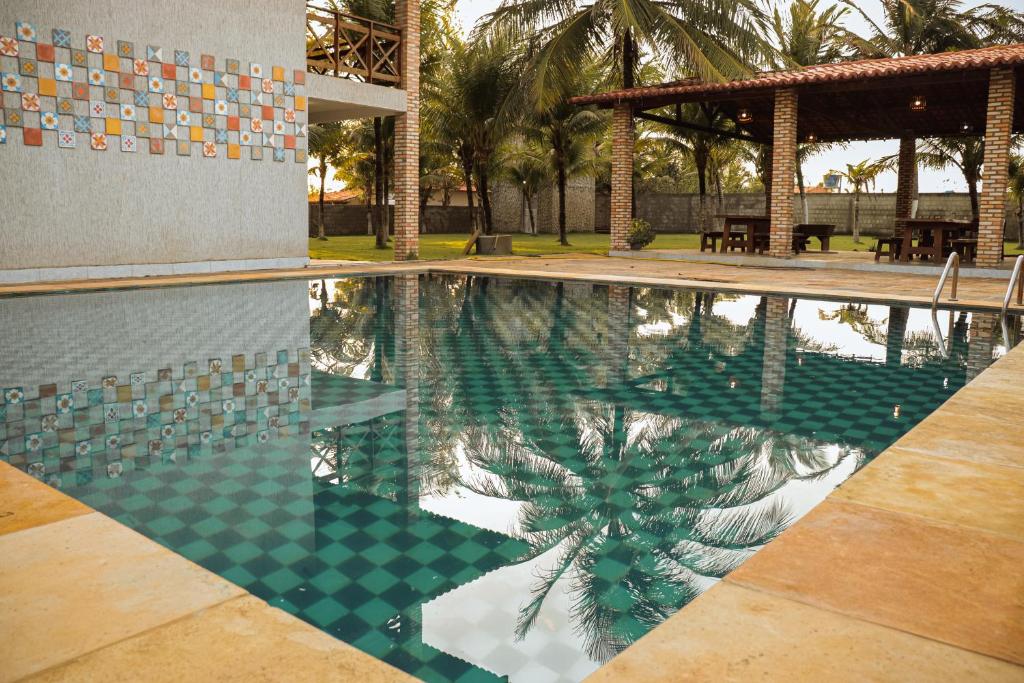 a swimming pool with a palm tree in front of a building at Orla Piaui in Luis Correia