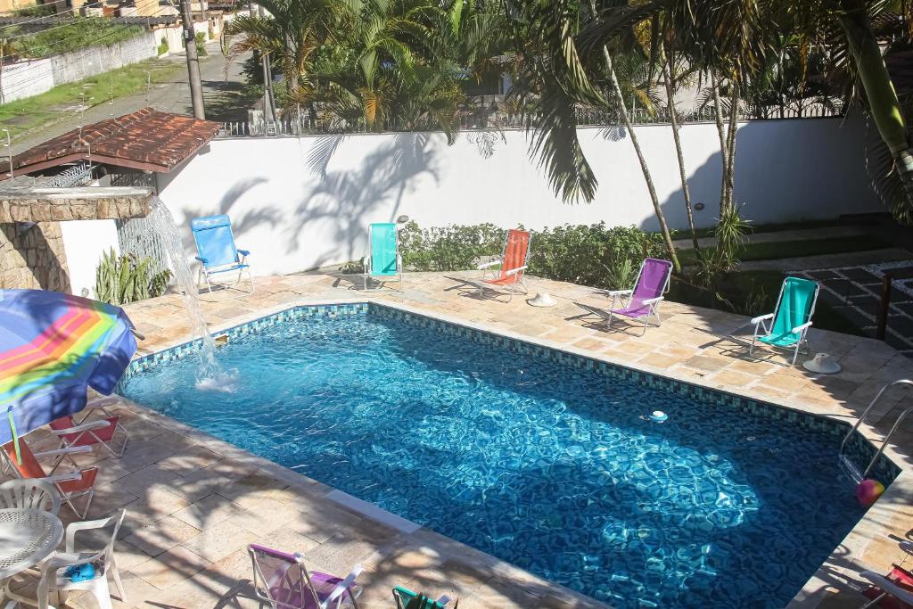 uma piscina com cadeiras e um guarda-sol arco-íris em MarLua Quartos & Suítes em Caraguatatuba