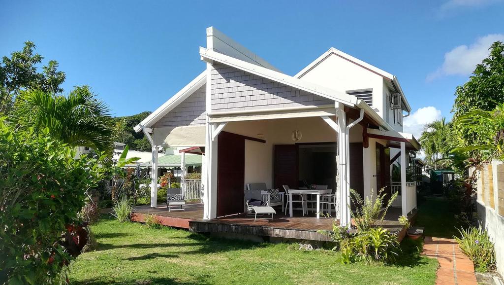 a white house with a porch with a table at cocon caraibe in Sainte-Anne