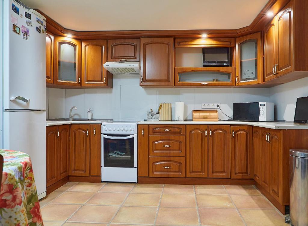 una cocina con armarios de madera y electrodomésticos blancos en White House, en Truskavets
