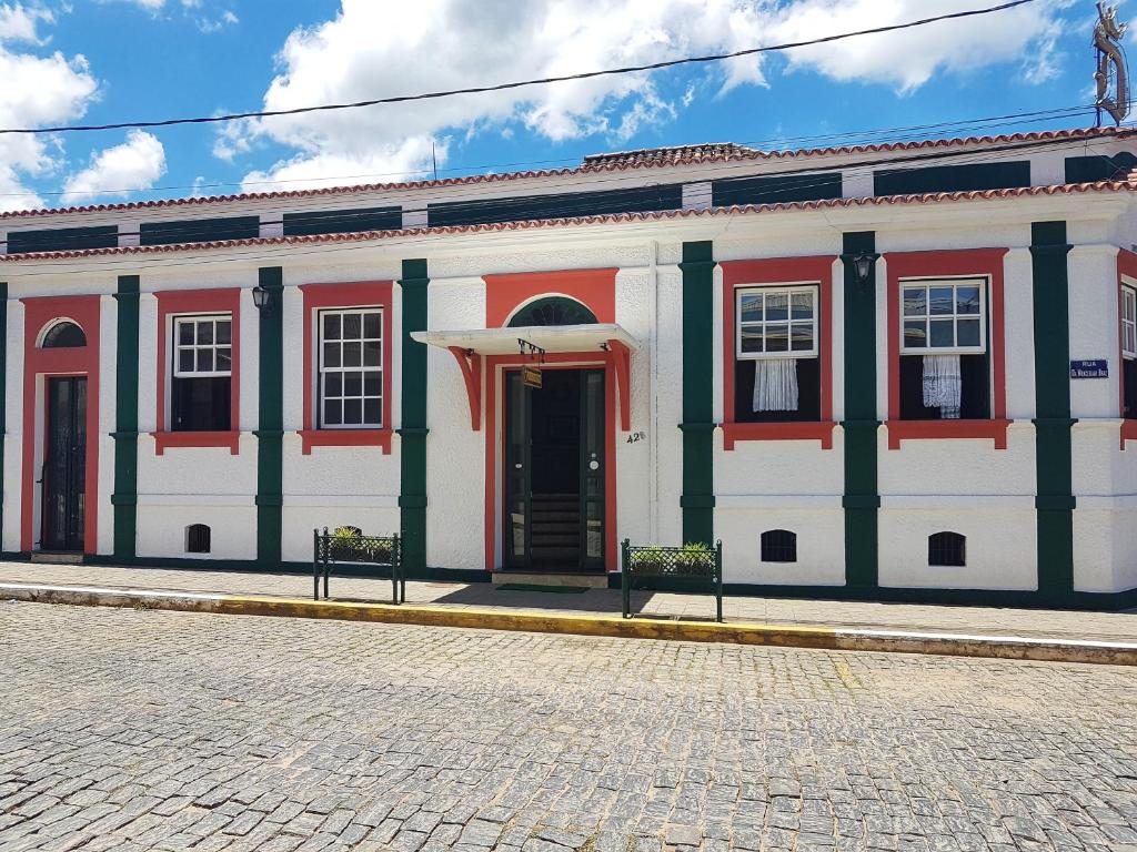 a large white building with red and green trim at Pousada do Duque in Lambari