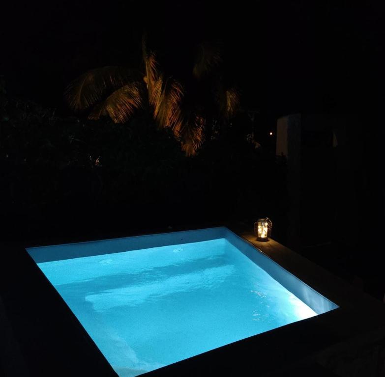 a blue swimming pool at night with a candle at Ocean BAYALOCATION in LʼAnse Mitan