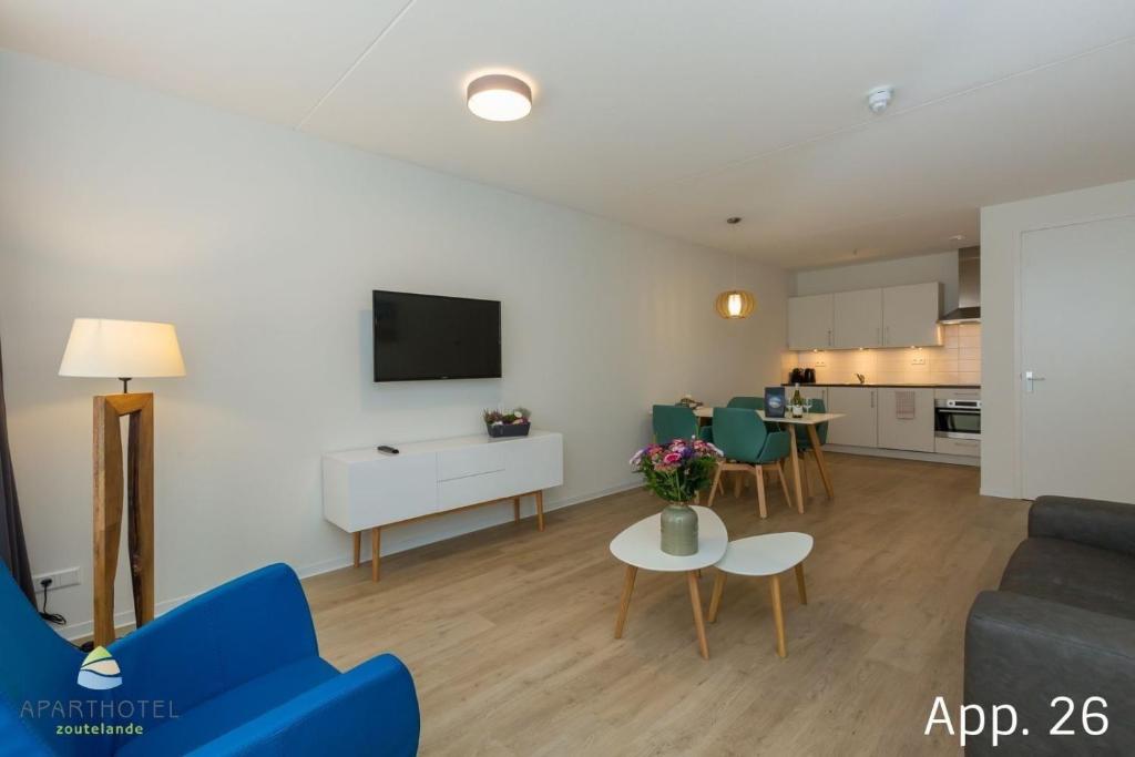 een woonkamer met een blauwe bank en een tafel bij Luxe 4-persoons appartement in Zoutelande
