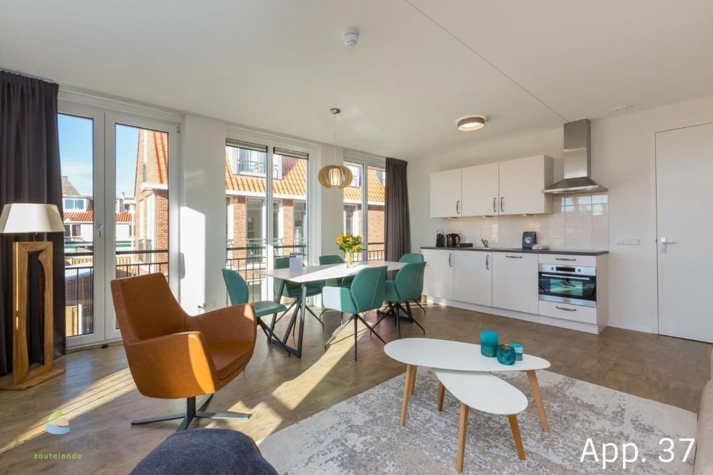 uma cozinha e sala de estar com mesa e cadeiras em Luxe 6-persoons appartement em Zoutelande