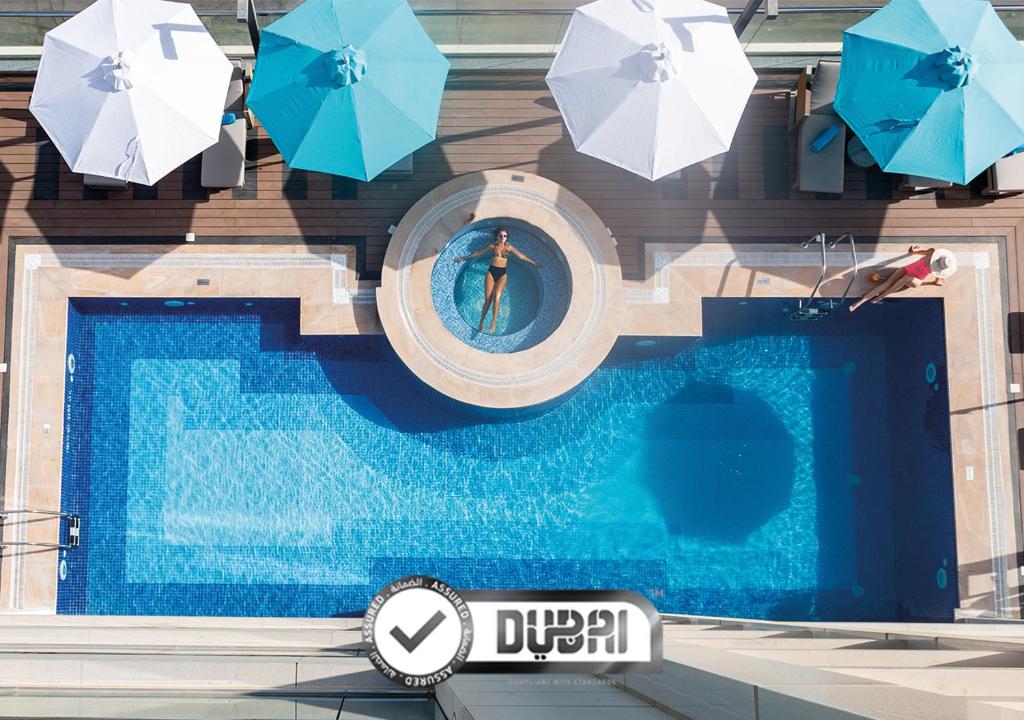 einen Blick über einen Pool mit Sonnenschirmen in der Unterkunft Edge Creekside Hotel in Dubai