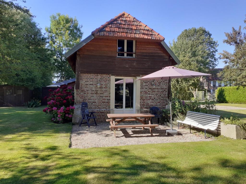 une petite maison avec une table de pique-nique et un parasol dans l'établissement Gîtes Manoir du Buquet, à Honfleur