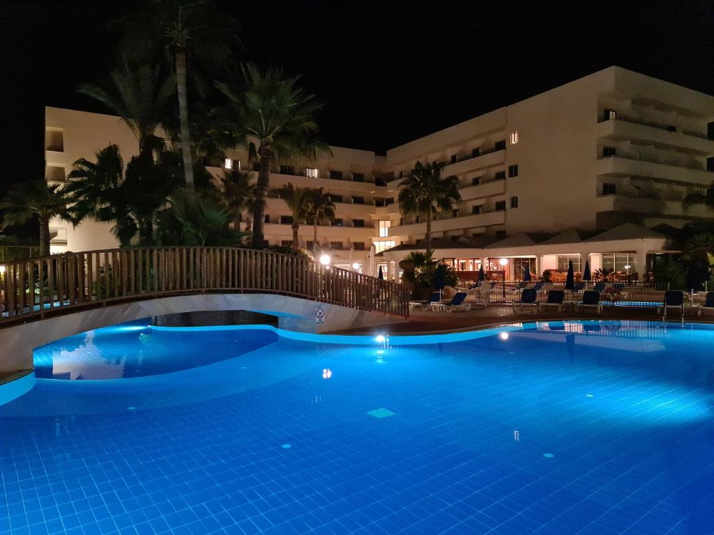 a swimming pool in front of a hotel at night at Nissiana Hotel & Bungalows in Ayia Napa