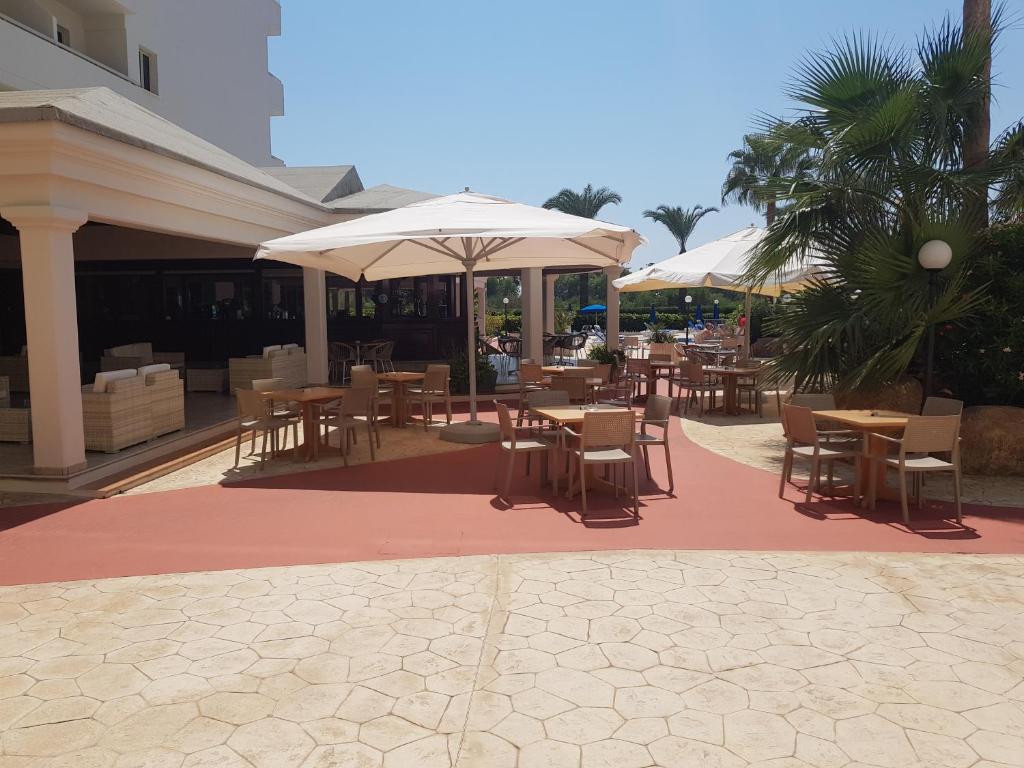 an outdoor patio with tables and chairs and umbrellas at Nissiana Hotel & Bungalows in Ayia Napa