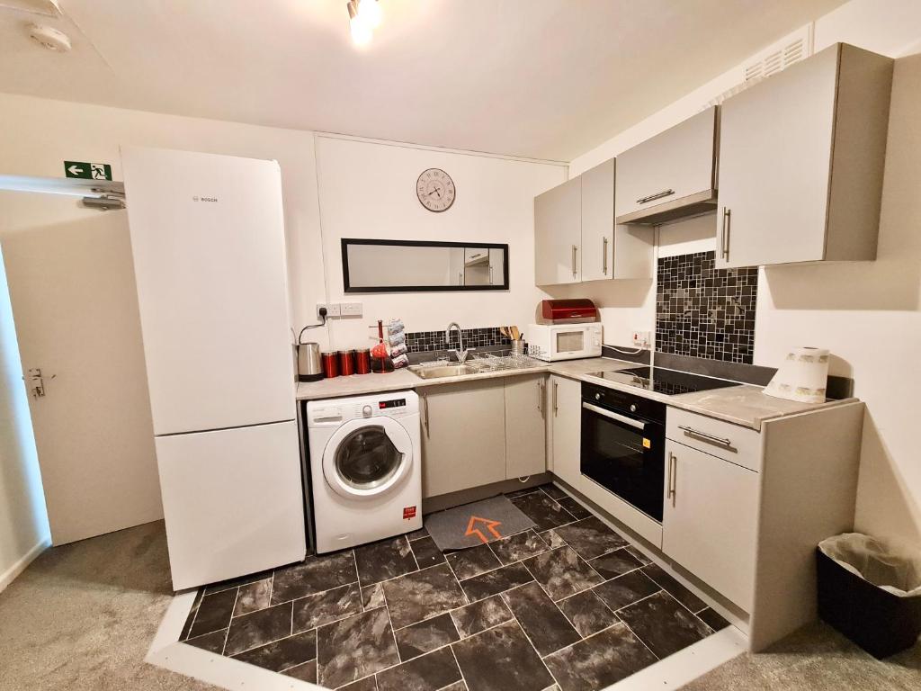 a kitchen with white cabinets and a washer and dryer at Grace Apartments - Living Stone 2 in Ashford