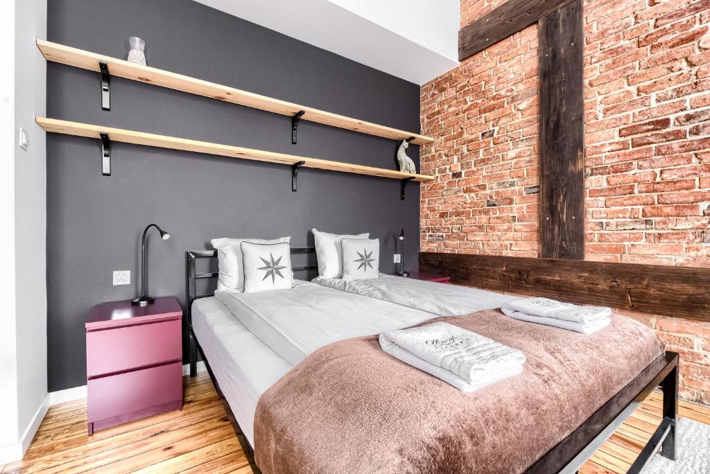 a bedroom with a large bed and a brick wall at MARGI Martini BIG BEAUTI STUDIO in Szczecin
