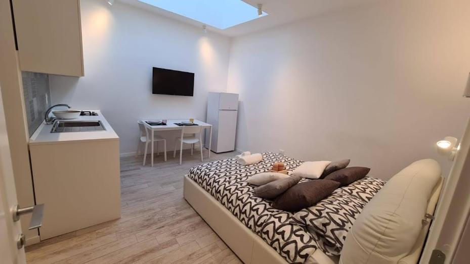 a small room with a bed with pillows and a kitchen at BARBARA Classy Apartment 101 in Siracusa
