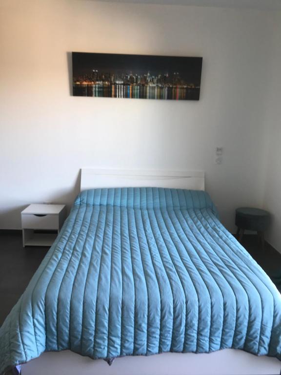 charmant studio dans résidence neuve et calme في كورتي: سرير مع لحاف أزرق في غرفة النوم